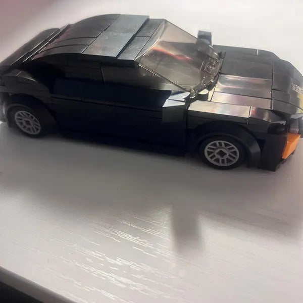 Dark brick coupe model with silver-colored wheels on a light surface
