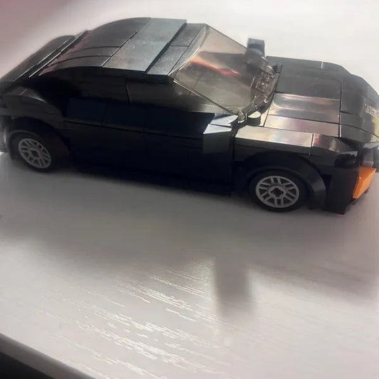 Dark brick coupe model with silver-colored wheels on a light surface