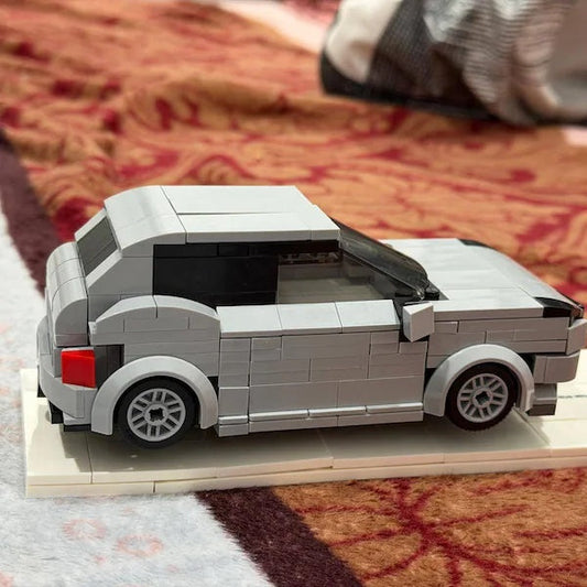 Silver brick hatchback in side view on a white base